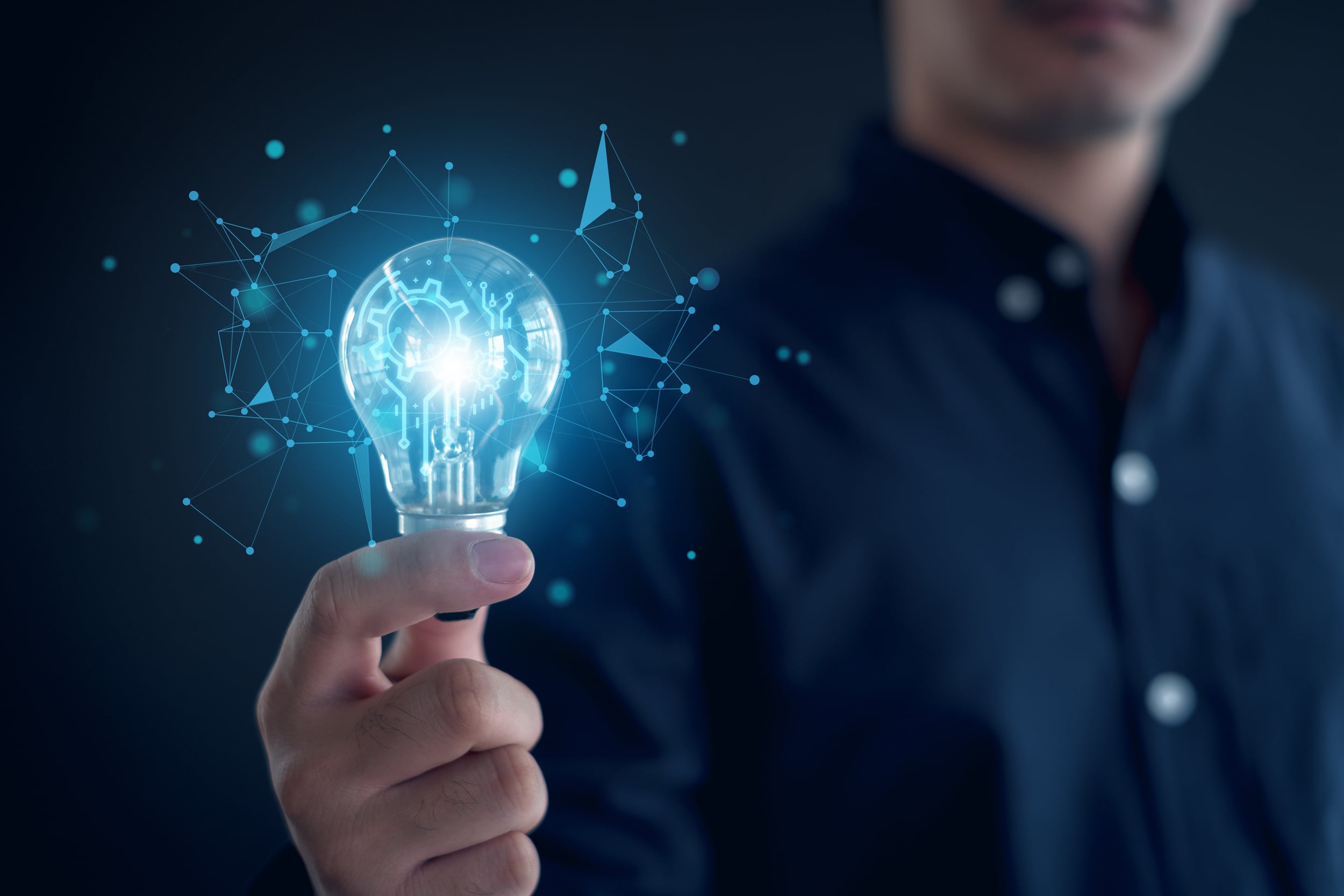 A man holds a glowing lightbulb. A matrix of ideas spill from the bulb as a metaphor for ideas and thoughts.