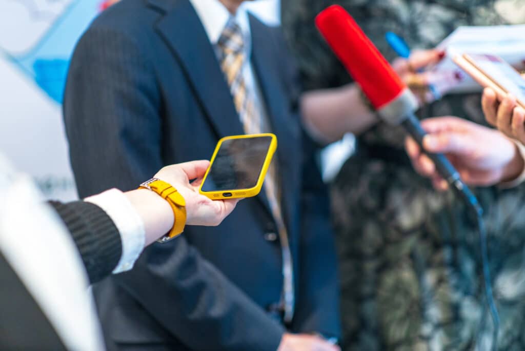 A woman holds out a phone to record a pr interview