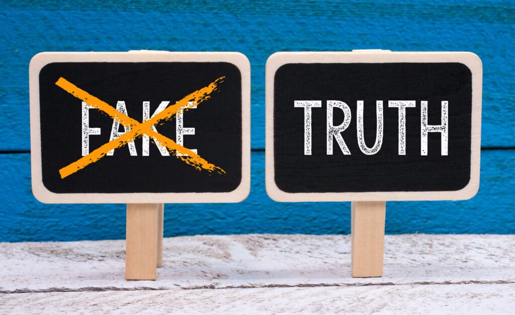 Two signs are in the frame, on with the word 'Truth' and the other with the word 'Fake'. Fake is crossed out.